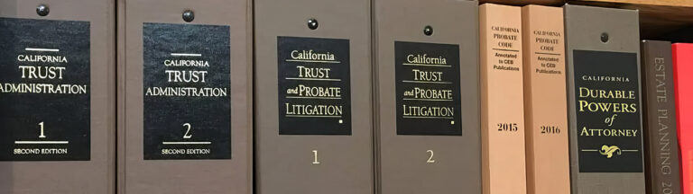 Close-up of a shelf with legal books on California trust administration, probate litigation, durable powers of attorney, estate planning, and California Probate Code. The books have brown, black, and beige covers.