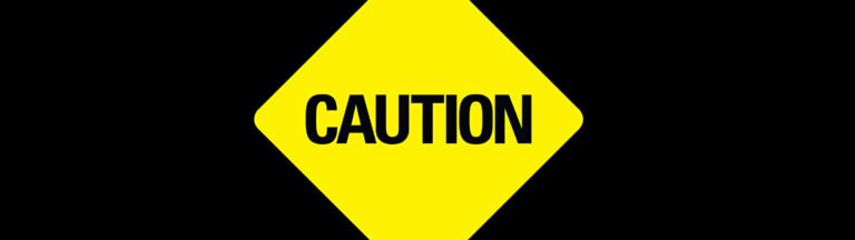 A yellow diamond-shaped sign with the word CAUTION in bold black letters on a black background.