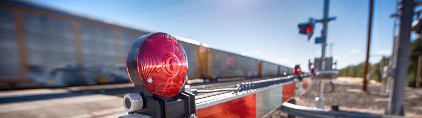 A red bar is blocking a train track to protect people from a speeding train.