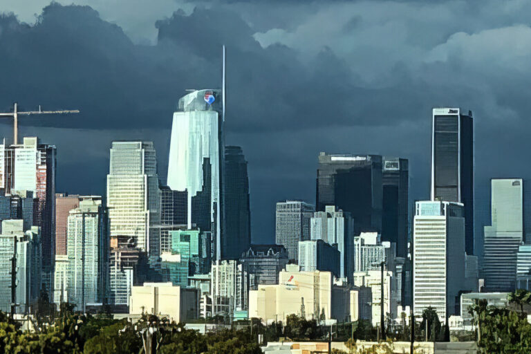 A panoramic view of downtown Los Angeles, featuring tall skyscrapers under a dramatic, cloudy sky, with palm trees and greenery visible in the foreground.
