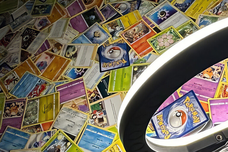 A ring light is positioned in front of a colorful wall covered with overlapping Pokémon trading cards, creating a vibrant and playful background.