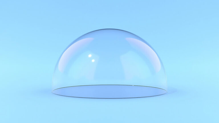 A transparent glass dome sits on a smooth, light blue surface against a matching blue background, with soft reflections and subtle hints of pink and purple on the dome.