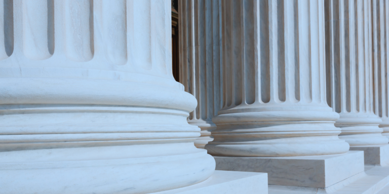 Close-up view of large stone columns with detailed bases, suggesting the entrance to a grand, classical-style building such as a courthouse or government building.