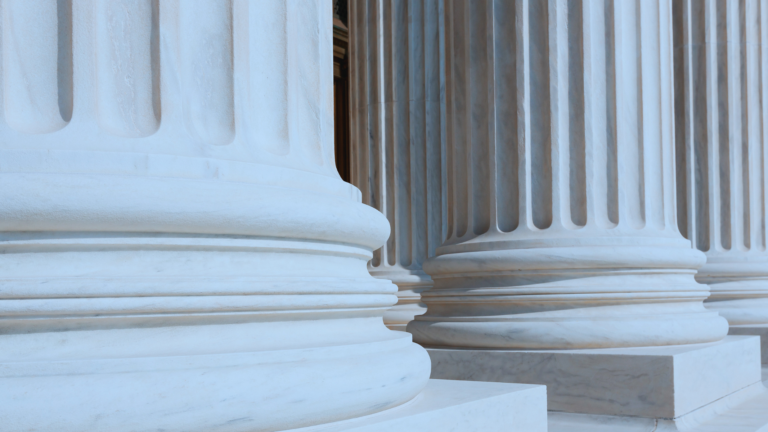 Close-up view of large stone columns with detailed bases, suggesting the entrance to a grand, classical-style building such as a courthouse or government building.