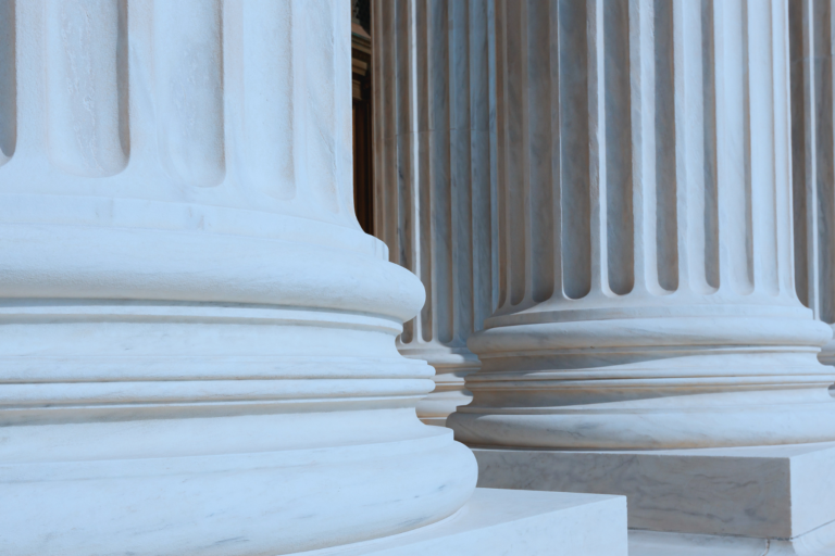 Close-up view of large stone columns with detailed bases, suggesting the entrance to a grand, classical-style building such as a courthouse or government building.